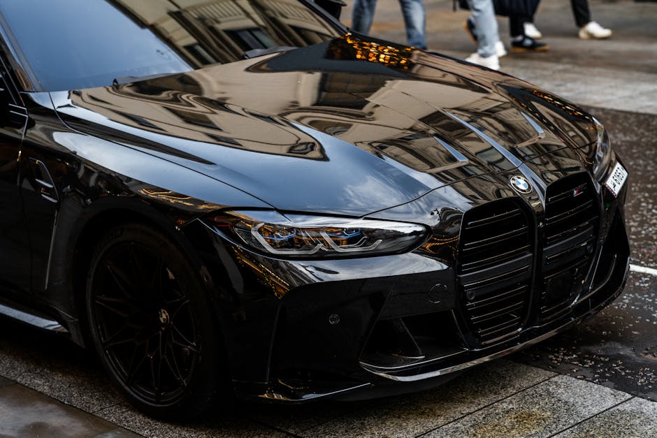A sleek black BMW M4 parked on a rainy London street
